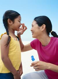 A mother applying sunscreen on her child to protect her from the sun.