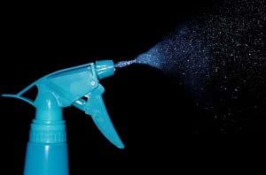 A spray mist cleaner squirted in front of a black background showing its mist.