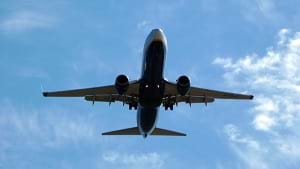 A photograph from the ground looking up at an airplane descending to land at Murcia San Javier airport in Spain.