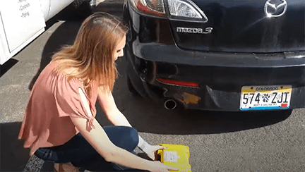 A photograph shows a person holding the air quality monitor near a pickup truck’s dual tailpipes. 