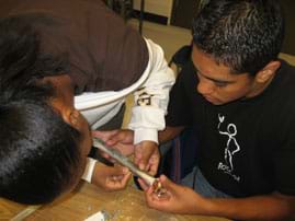 Photo shows two students holding and taping a six-inch bone.