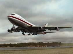 Photo shows a large streamlined airplane lifting off from a runway.