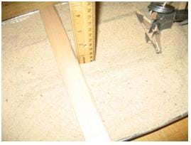 Photo shows a ruler placed vertically into the bottom of the furrow next to another ruler placed across the pan of sand, resting on the pan edges, providing a consistent level to which the depth can be measured.