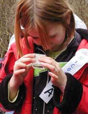 A girl looks intently at a jar in her hands.