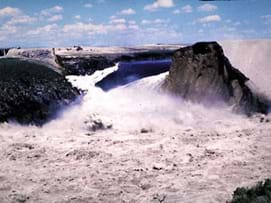 Photo shows water gushing through a break in the wall of a dam.