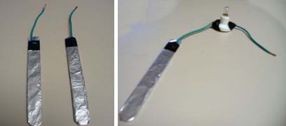 Two photos: (left) Two long, flat silver paddles, each with a wire coming out of one end. (right) A long, flat silver paddle wired to a miniature light bulb socket, with another wire leaving the other side of the socket.
