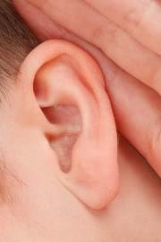 A close-up photograph of a person's ear and hand.