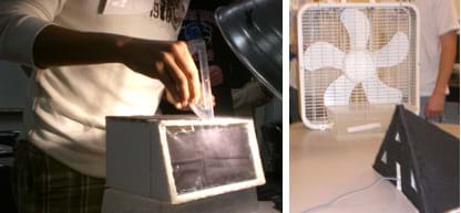 Two photos: A student uses a protractor to position the angle of a desk lamp shining on a box-shaped structure of foam core board with a plastic window wall. A box fan on a table blows air past a plastic container of ice towards a black foam core model house with a pitched roof, windows and a door.
