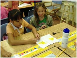 A photograph of two students reverse engineering a sunflower. Shown are the flower petals scattered on a white sheet of paper.
