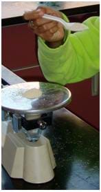 A photograph of a student measuring out the correct amount of yeast using a triple beam balance.