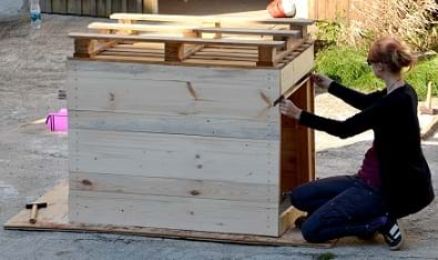 A student using a ruler to measure the width of a wooden box.