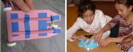 Two photos: (left) The undercarriage of a mint-mobile shows folded index cards and cut straws taped to form axles and structural support. (right) Two young girls work together using their hands to make a blue car made of paper, straws and lifesaver-shaped candies (for wheels).