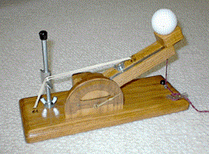 An example wooden catapult model made with a wooden block, nails, string, equipped with a ball ready for launch.