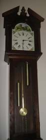 A grandfather clock with a rod pendulum swinging below the clock face.