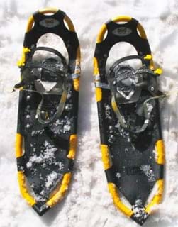 A close up photograph shows a matching pair of black and yellow snowshoes.