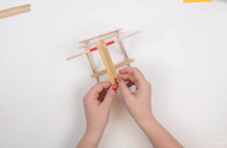 A gif showing the stretching out of the rubber band and testing the rotation around wooden dowel.