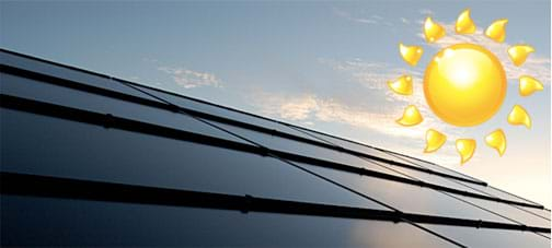 Sunlight reflects off sheets of shiny dark blue photovoltaic panels covering a rooftop.