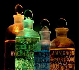 Four flasks containing different chemicals (including Ammonium hydroxide and Nitric acid) lit in different colors.
