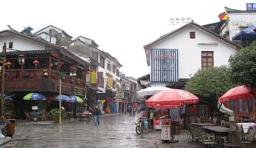 Photo shows a street flanked with two-story white-washed homes with tile roofs.