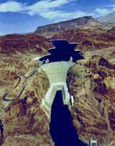 Aerial photo shows a concrete dam blocking a river's passage in a dry environment.