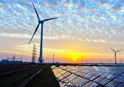 Sun comes up over power lines, wind turbines and solar panels