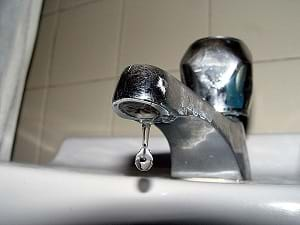 A drop of water dripping from an indoor faucet 