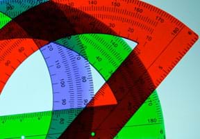 A photograph shows three overlapping translucent plastic protractors of different colors, blue, green and red. The devices are semi-circular in shape. Markings show inches and degrees.