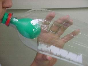 Photograph of an un-stretched balloon inside a two-liter bottle with the open end of the balloon stretched over the bottle lip
