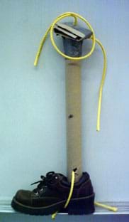 A photograph shows a shoe bound to a cardboard tube with ropes.