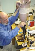 Photo shows man assembling prosthetic leg that has a hydraulic knee system.