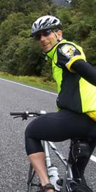 A photograph shows a man riding a bike, wearing cycling clothing, helmet and wrap-around sunglasses.