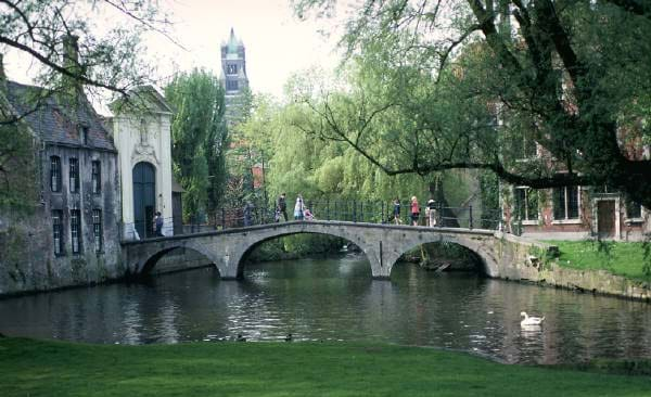 Photo shows an old stone bridge with three arches across a stream.