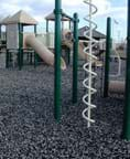 A photograph shows a playground play set surrounded by gravel.