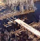 A photograph shows a wooden bridge in construction over a stream.