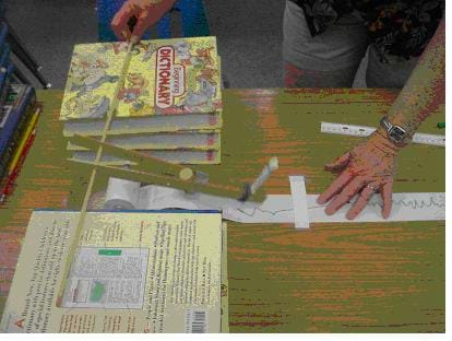 A photograph of someone using a homemade seismograph constructed out of common classroom materials.