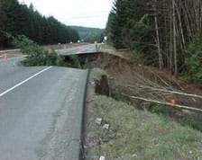 Photo shows a highway with an enormous sunken crater, large enough to fit a semi truck.