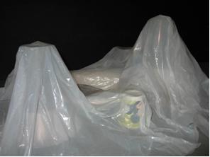 A photograph shows a sheet of white plastic draped over many objects, looking like a hilly terrain.