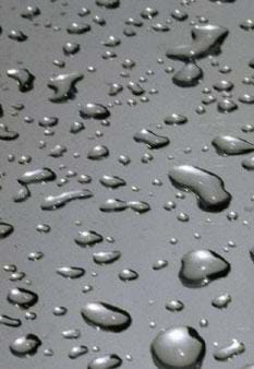 A photograph shows water droplets on a gray surface.