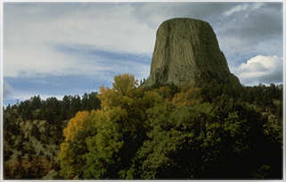 Photo shows a huge, square rock, much higher then the surrounding trees.