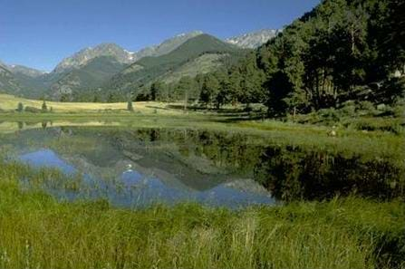 A photograph shows a u-shaped valley of mountains with a lake in the foreground of the valley.