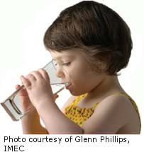 A photograph of a young girl drinking water from a glass.