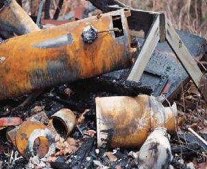 A photograph shows a pile of trash — cans and scraps of metal — that are in various stages of breakdown.