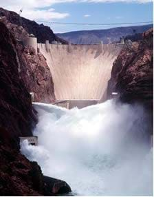 A photograph shows a huge concrete dam holding back a reservoir of water in a narrow rocky canyon.