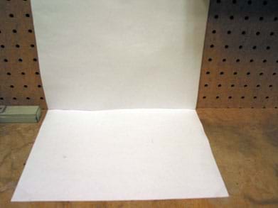 Photo shows two pieces of white paper affixed perpendicularly, to a wall and a table top.