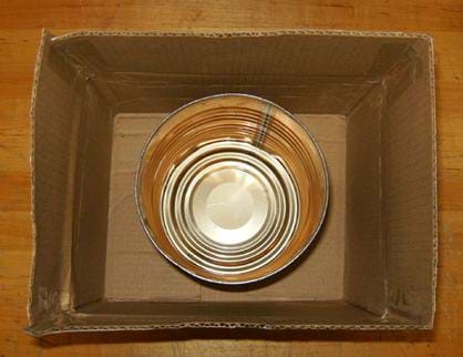 A photo looking down into a cardboard box with an open metal coffee can placed at the bottom.
