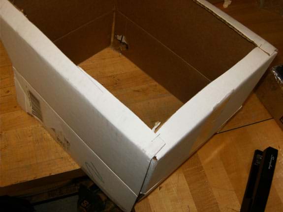 Photo shows the bottom of a cardboard box with the cardboard cut away except for a one-inch edge on the four sides.