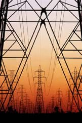 Photo shows many tall electrical towers and wires stretching into the horizon.