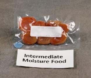 Seven flat orange apricots encased in plastic. A small sign below the bag reads: "Intermediate Moisture Food." 