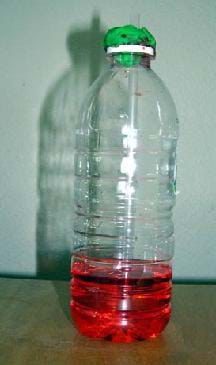 Photo shows a water bottle one-quarter filled with red liquid. A straw sticks out of the bottle opening, with green clay holding it in place.