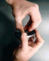 Photo of two hands trying to separate a magnet from a metal plate.